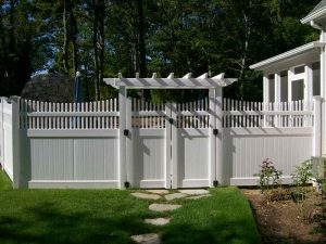A white vinyl fence gate with lattice design, installed in a residential backyard, showcasing modern and stylish gate ideas for homes.