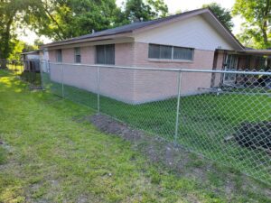 "Chain link fence surrounding a Houston house with a well-maintained lawn."