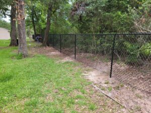 "Chain-link fence surrounding a lush yard with mature trees in Houston, perfect for fencing and gates services."