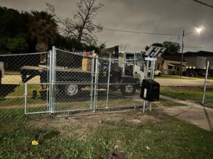 "Chain link gate and fence in Houston, Texas, illuminated under the night sky."