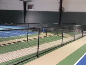 "Indoor tennis court enclosed by a chain-link fence in Houston, TX."