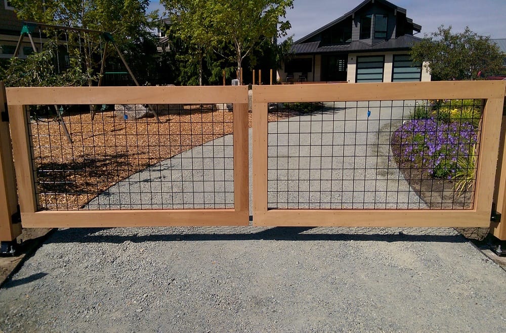 Cedar-clad wooden driveway swing gate matching a privacy fence in Houston