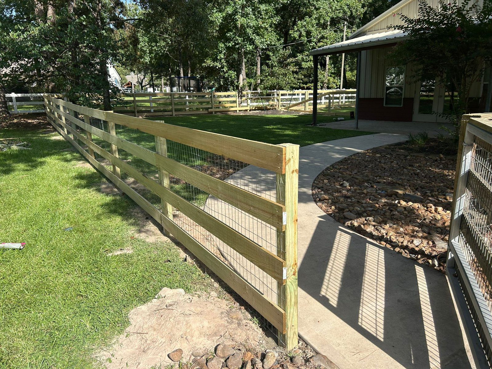 Three-rail wood ranch fence with wire mesh backing installed near Houston