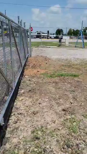 Galvanized chain-link cantilever slide gate at a gravel commercial lot entrance