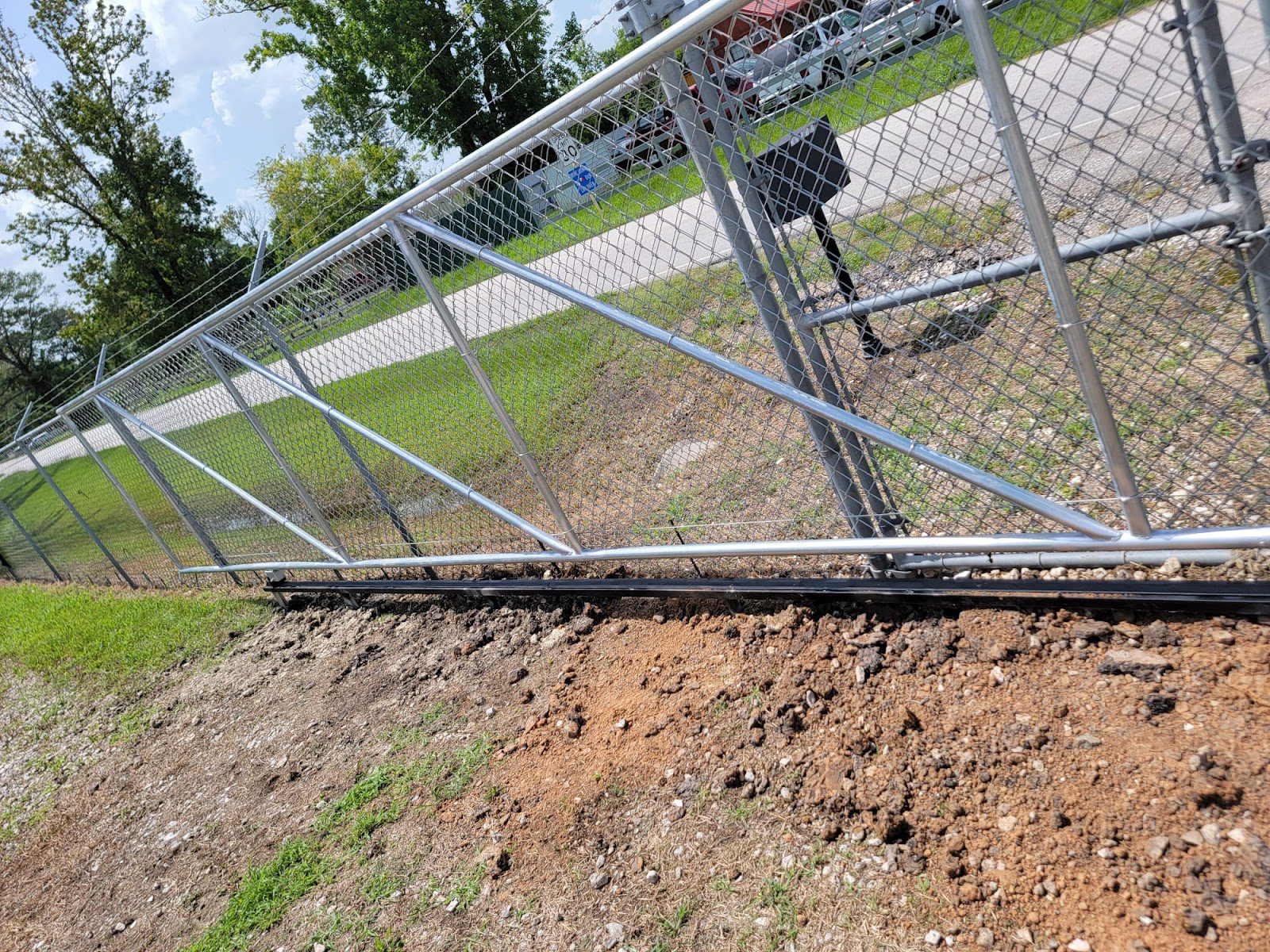 Galvanized chain-link cantilever sliding gate with a diagonal support truss along a roadside
