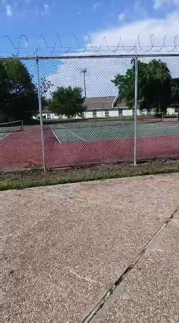 Galvanized chain-link fence topped with barbed wire enclosing a sport court near Houston