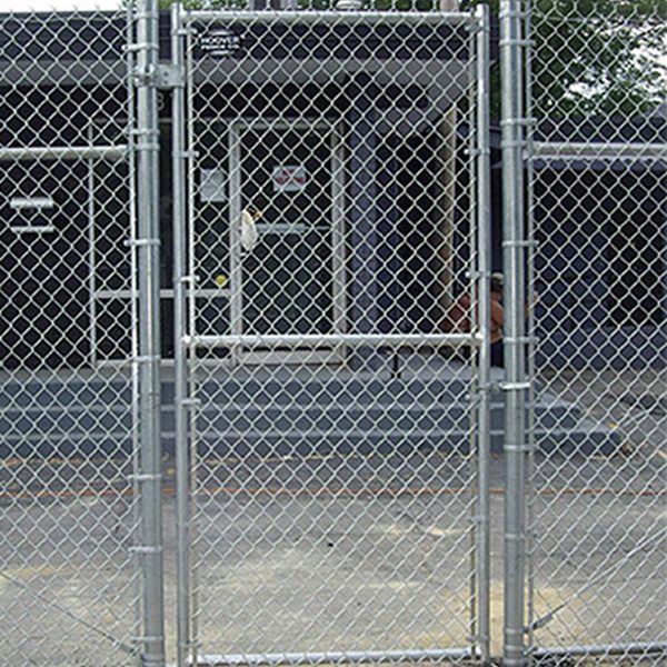 Small galvanized chain-link pedestrian man-gate within a perimeter fence at a utility equipment enclosure