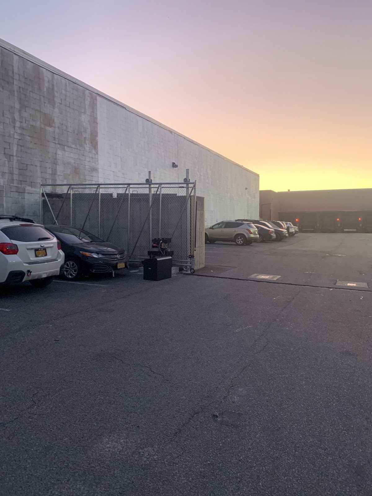 Galvanized chain-link cantilever slide gate partly open beside a large commercial building at dusk near Houston