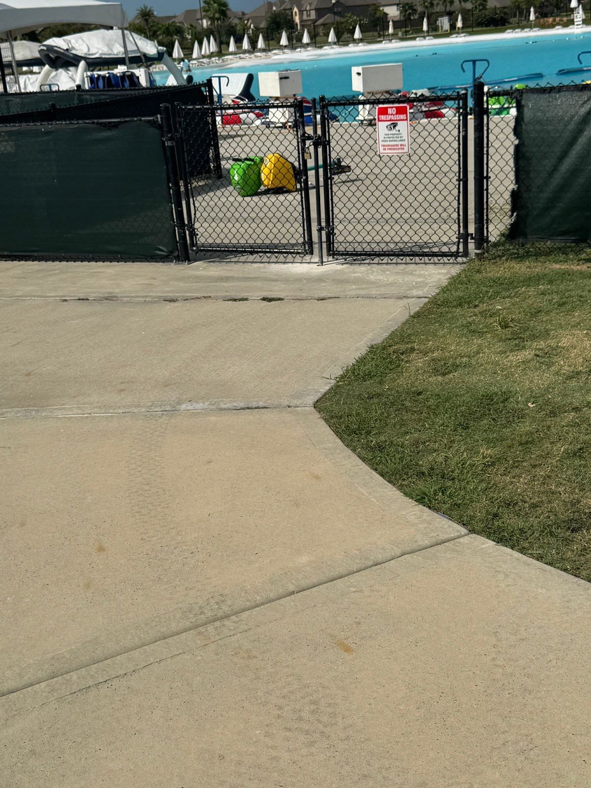 Black chain-link swing gates with privacy screen fronting a commercial pool amenity area