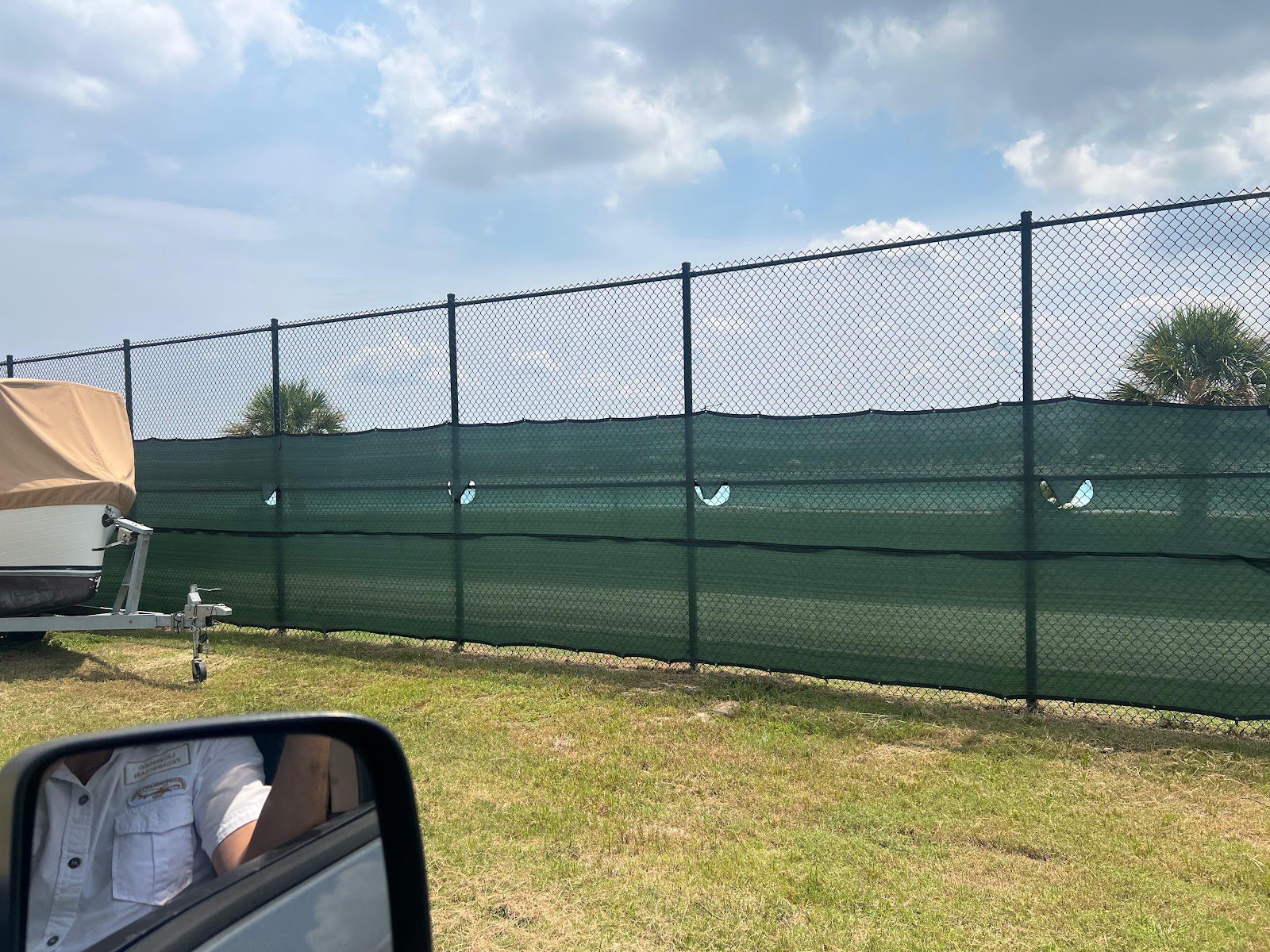 Black chain-link fence with green privacy windscreen bordering a storage lot near Houston