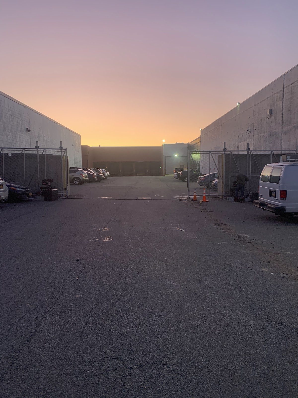 Dusk view of a commercial loading yard flanked by two galvanized chain-link cantilever slide gates in the Houston area