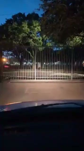 Illuminated iron slide gate at a Houston-area property entrance, photographed at night