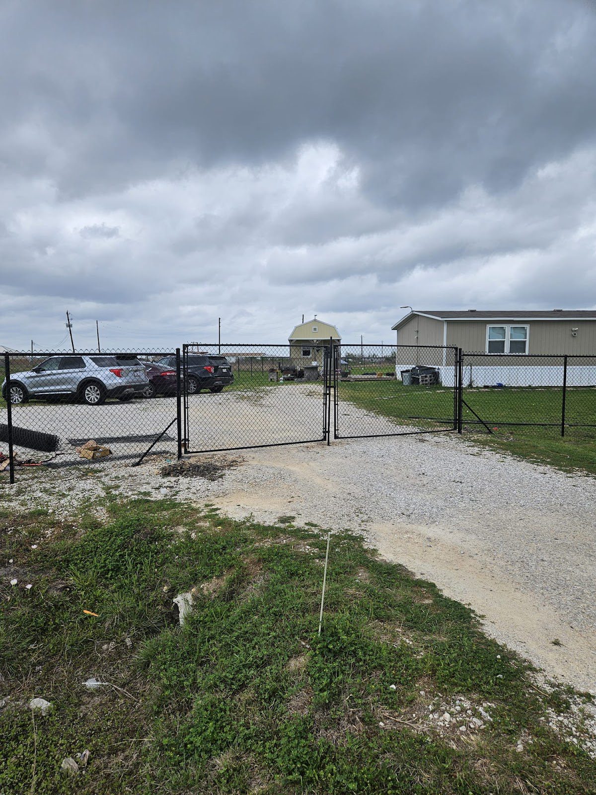 A lockable black chain-link double swing gate spanning a wide drive entrance, sized for full vehicle access.