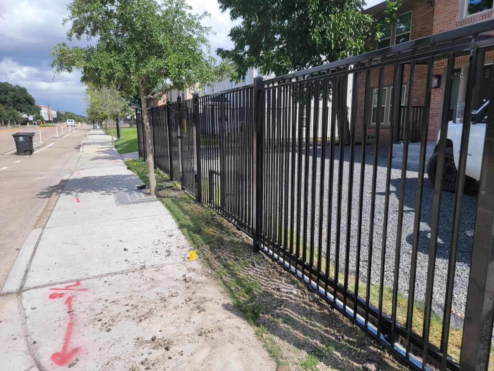 A black steel security fence and swing gate secure the entrance to a multi-family apartment community, controlling resident and visitor access.