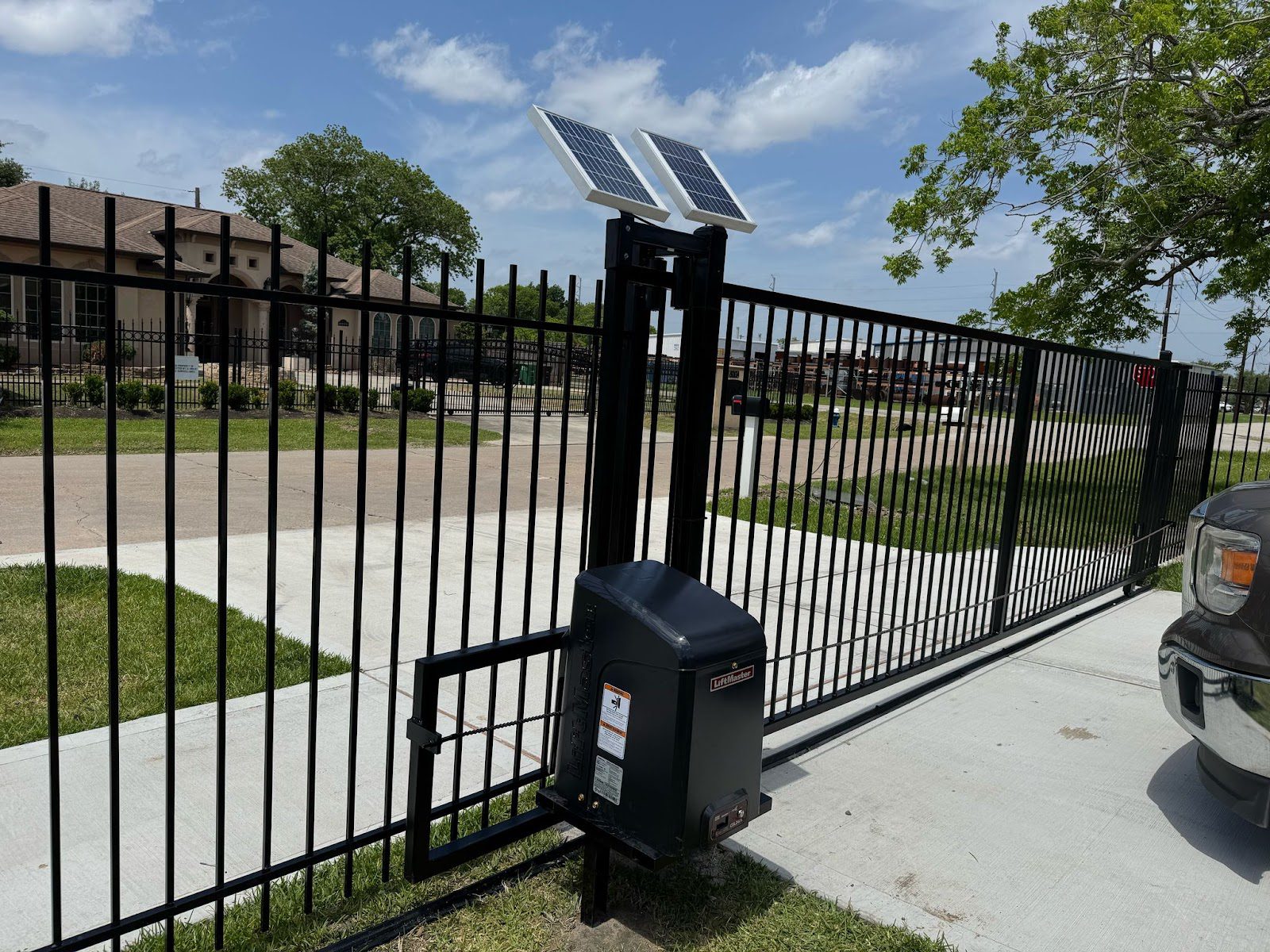A solar-powered LiftMaster automatic slide gate secures a commercial driveway with a dedicated access-control pedestal at the entry lane.