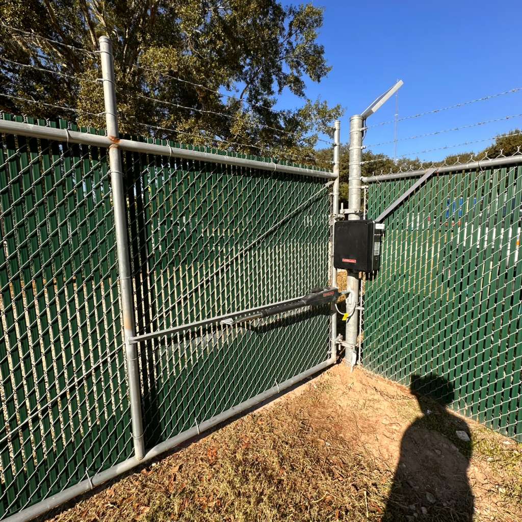 A solar-powered gate operator and weather-rated control box manage automated access for a secured commercial yard.