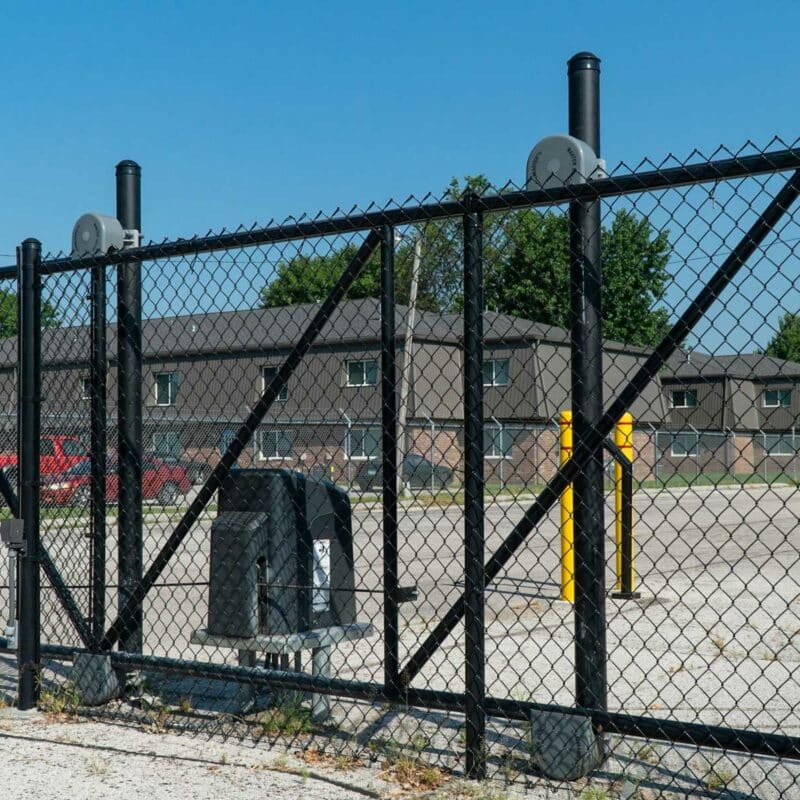 An automated chain-link cantilever slide gate with safety bollards manages entry at a gated multifamily and institutional property.