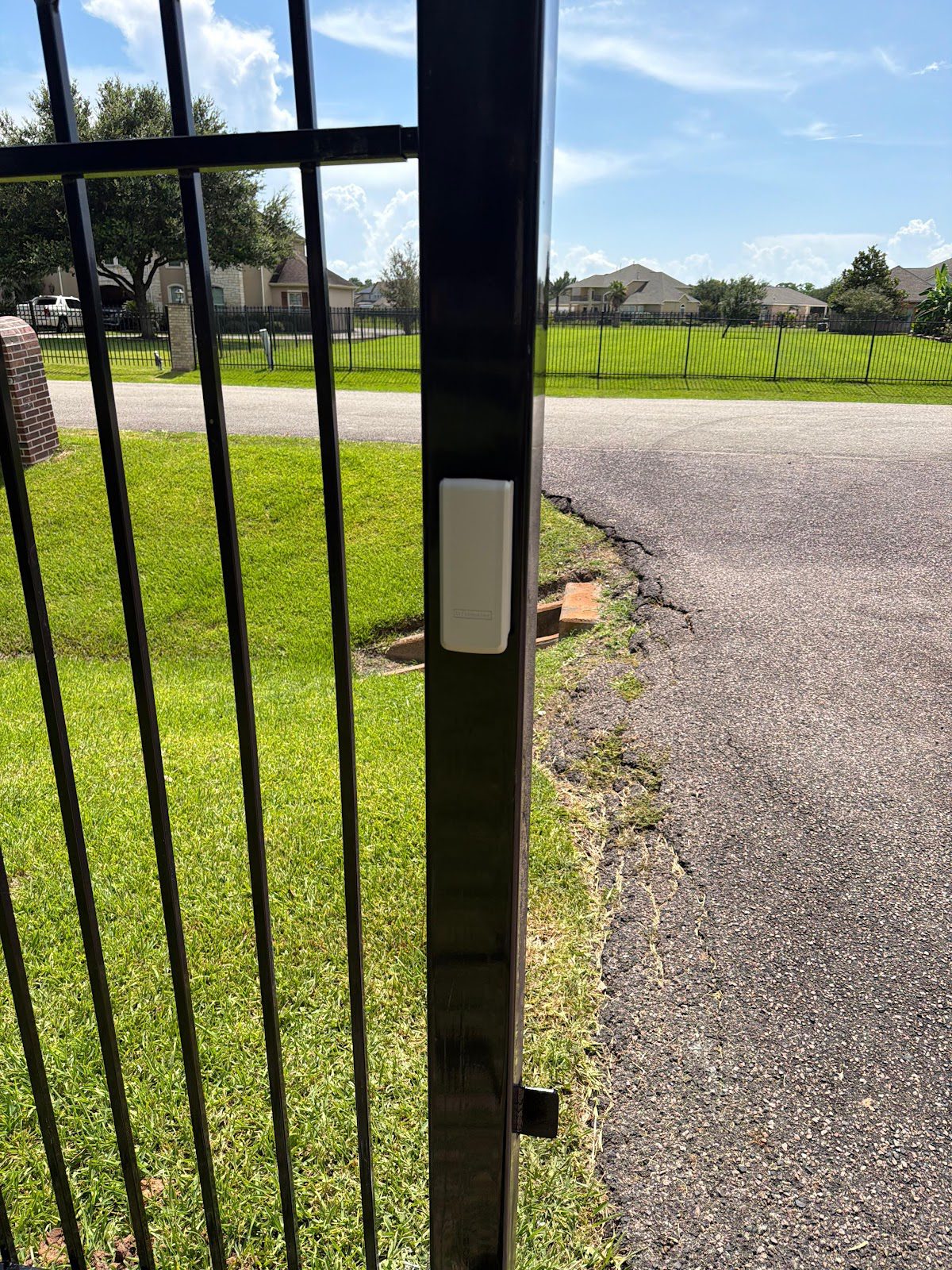 Close-up of a black steel gate frame with entry hardware mounted on the post at a Houston-area residence