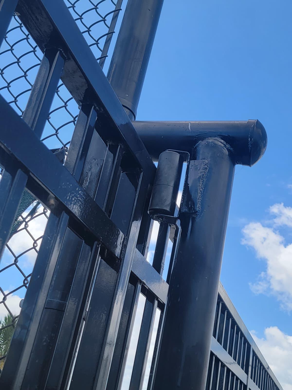 Close-up of a freshly painted black steel gate showing the welded hinge and post joint detail