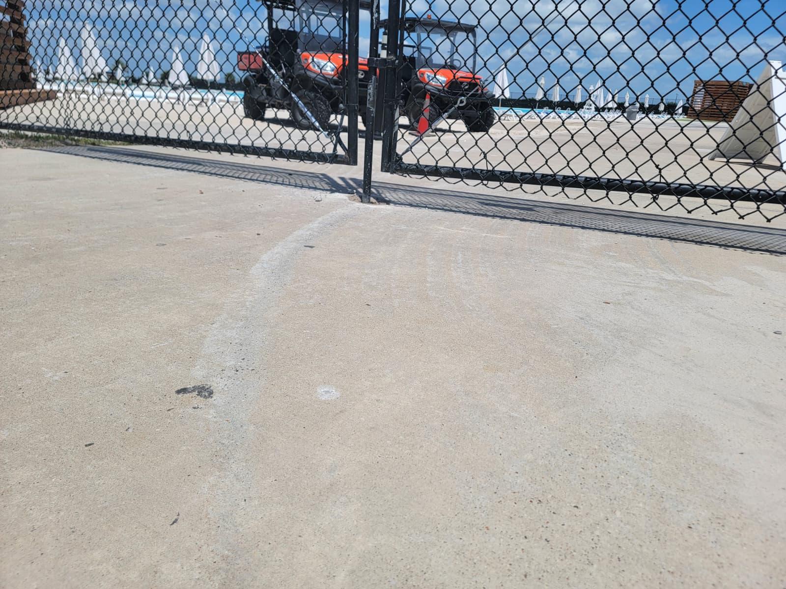 Black vinyl-coated chain-link fence with a swing gate enclosing a commercial pool deck