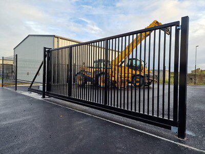 Black steel vertical-bar cantilever slide gate at a commercial warehouse entrance in the Houston area